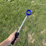 Telescoping golf ball retriever near a pond.